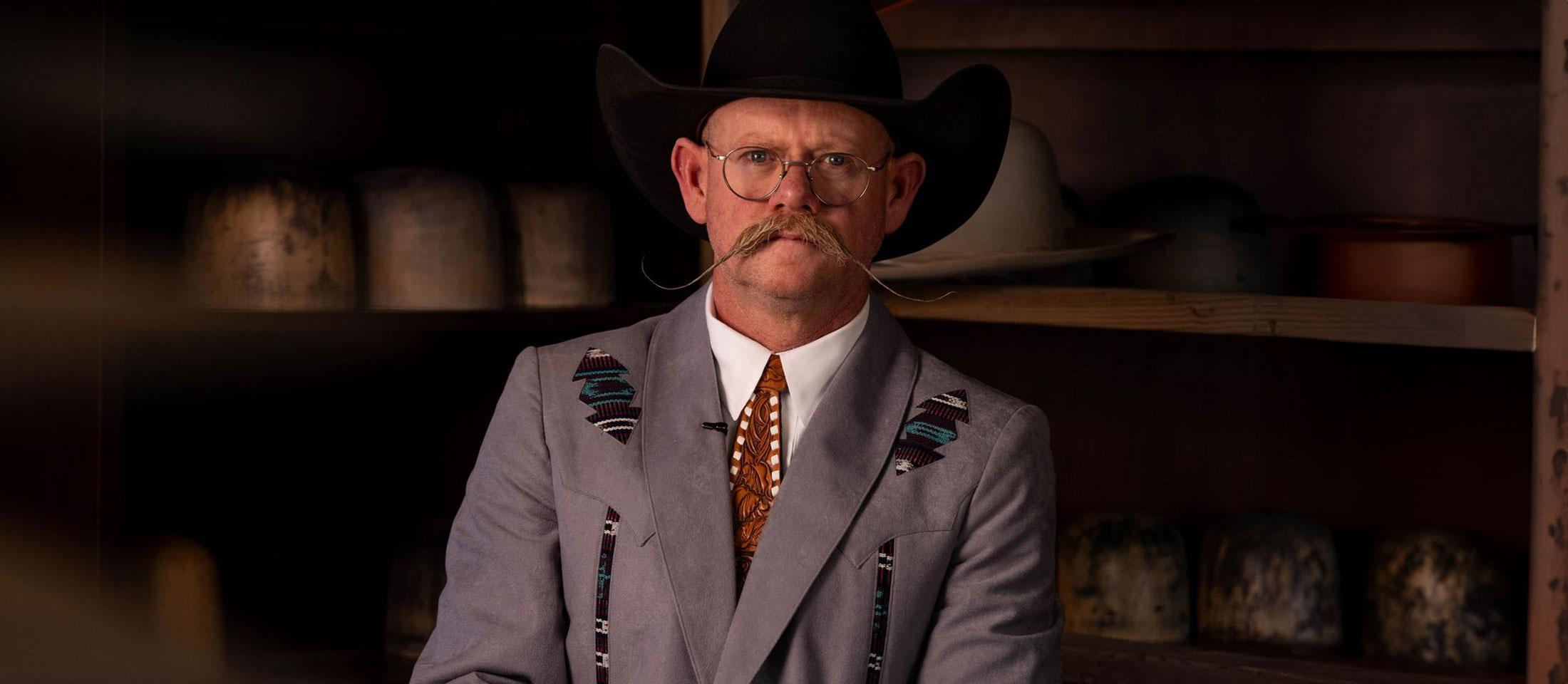 A man, Chaz Mitchell, standing in front of his hat bar and his hat tools.